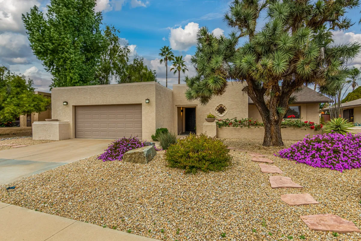 This exterior shot captures decorative landscaping with colorful flowers and a pathway lined with stepping stones. The soft lighting suggests a perfect backdrop for outdoor dinners or gatherings under the stars.