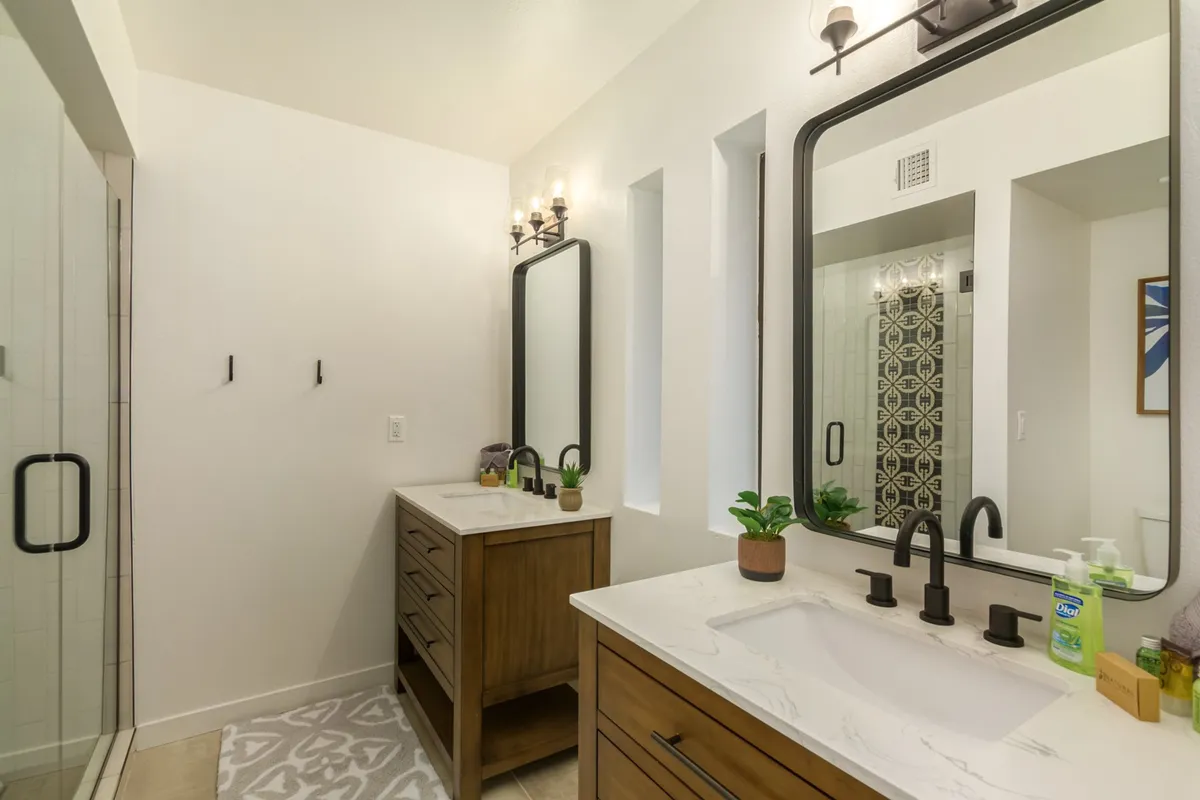 A spa-inspired bathroom featuring a contemporary vanity with dual sinks, sleek modern mirrors, and decorative wall tiles. The clean lines and soothing lighting evoke a sense of luxury and rejuvenation.